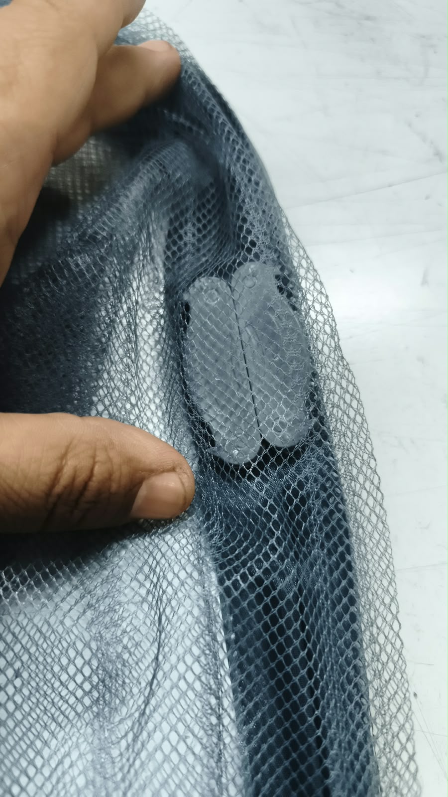 Detalle de la malla con una pieza de sujeción, en la mano